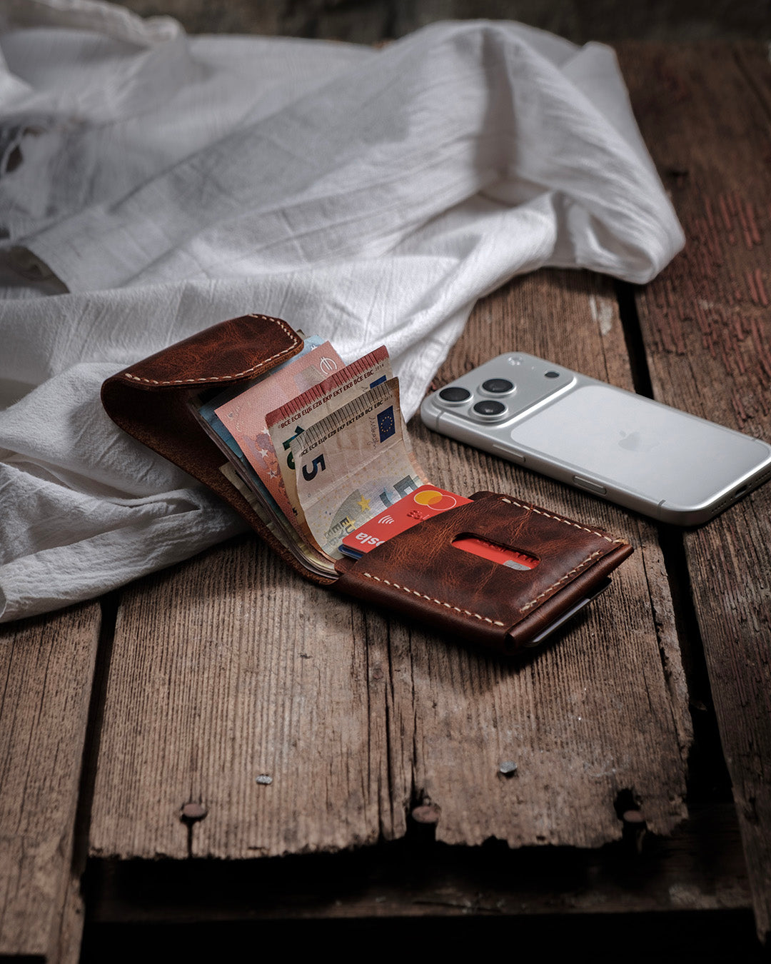 Dogaart Athen brown waxed pull up leather wallet open showing multiple banknotes with iPhone 17 Pro comparison