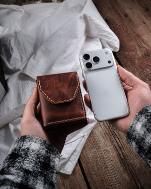 Dogaart Athen brown waxed pull up leather wallet closed beside iPhone 17 Pro demonstrating smaller dimensions