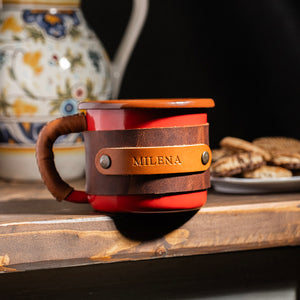 Travel enamel mug with handcrafted leather sleeve, ergonomic handle design, front profile view