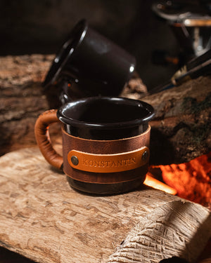 Leather wrapped enamel mug featuring embossed branding on premium leather sleeve, front profile view