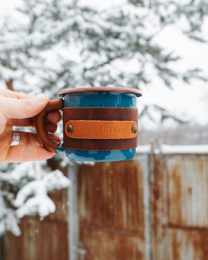 Travel mug with leather sleeve designed for hiking and outdoor use, comfortable grip demonstration in hand