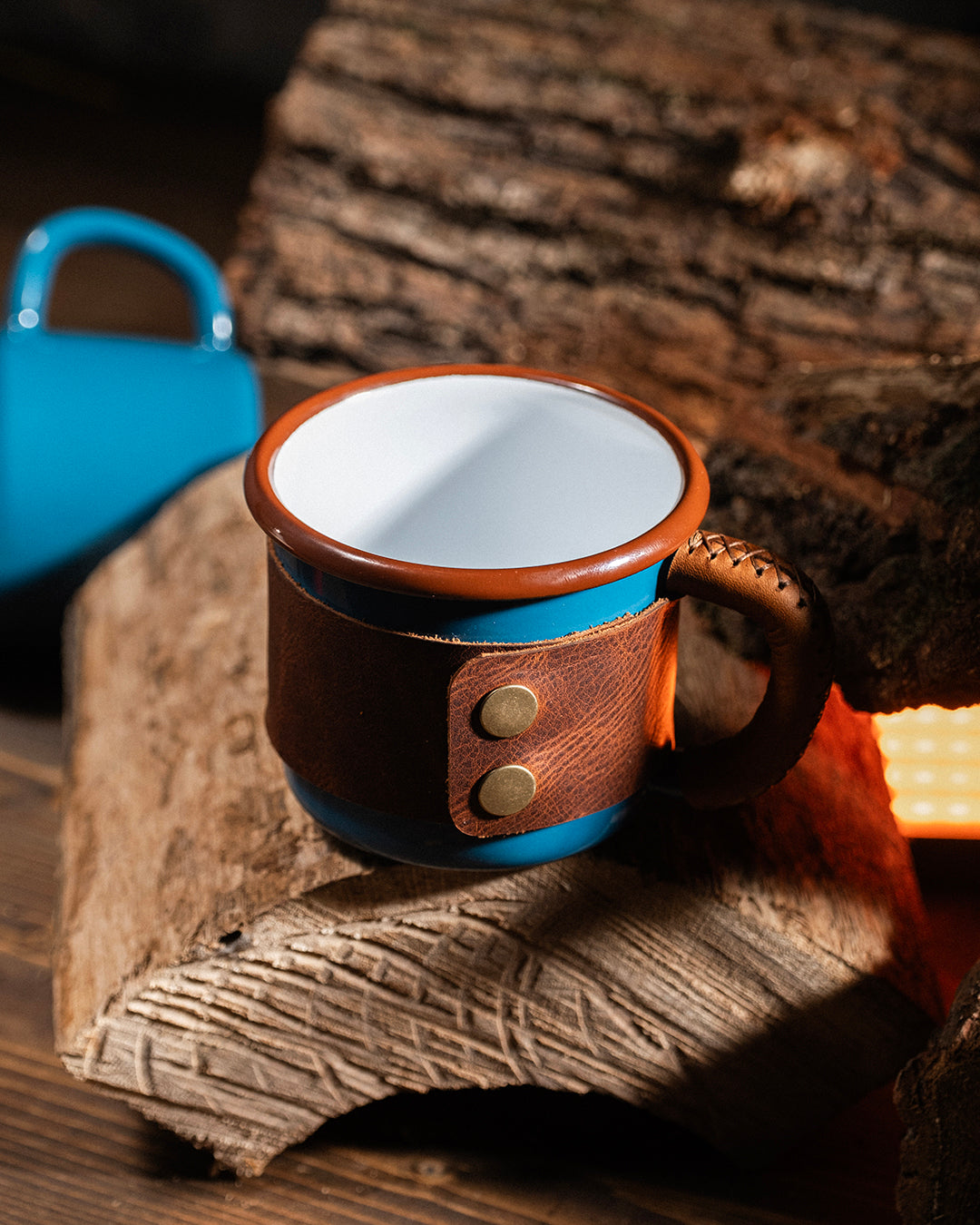 Premium leather wrapped enamel mug featuring stainless brass snaps securing handcrafted sleeve, close-up hardware detail