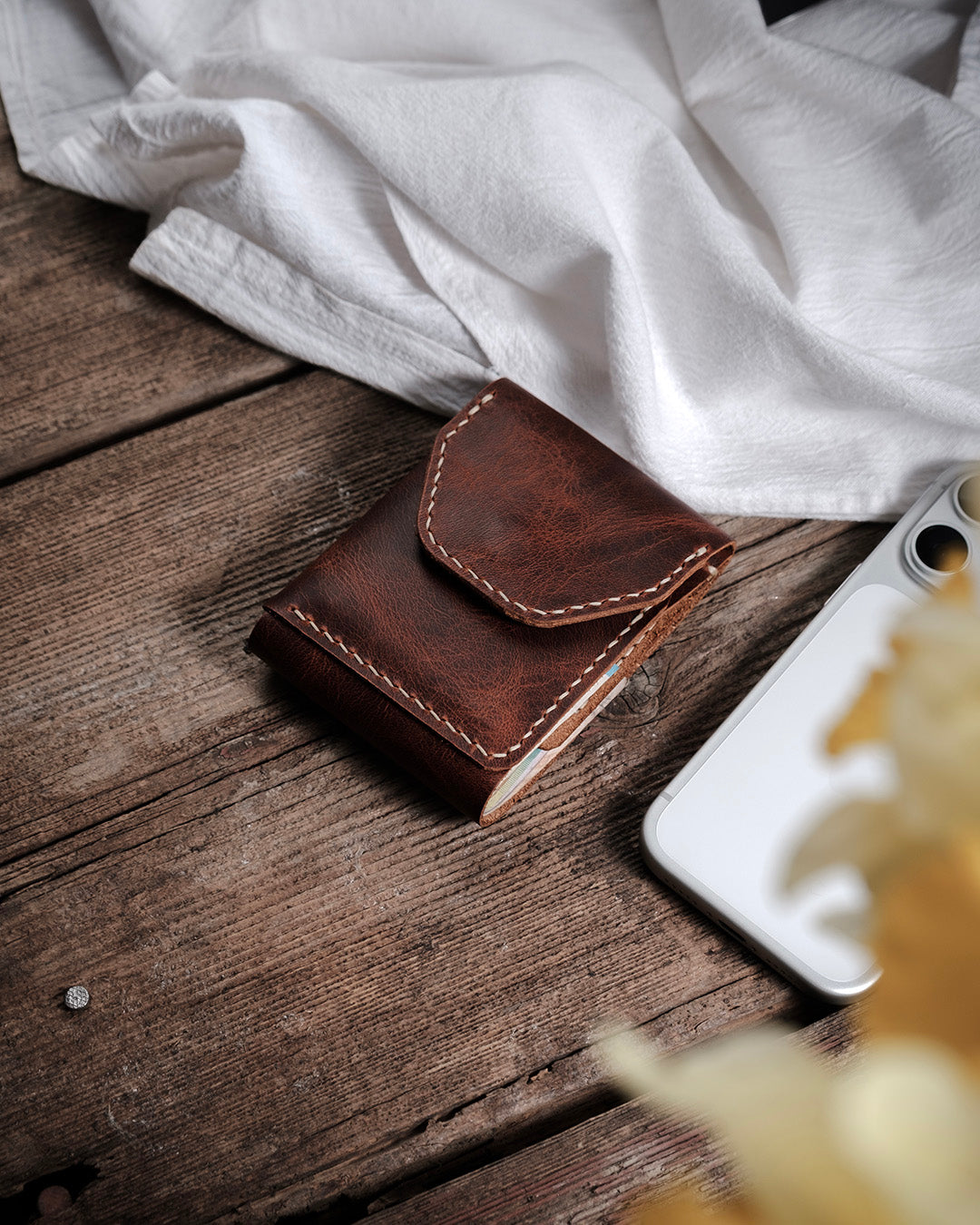 Dogaart Athen brown waxed pull up leather wallet on desk showcasing grain texture and contrasting cream stitching