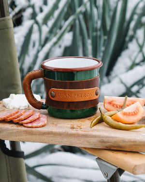 Dogaart green enamel mug with genuine leather wrap featuring 330ml capacity shown in straight-on front view