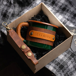 Green leather-wrapped enamel mug nestled inside elegant gift box packaging ready for premium presentation