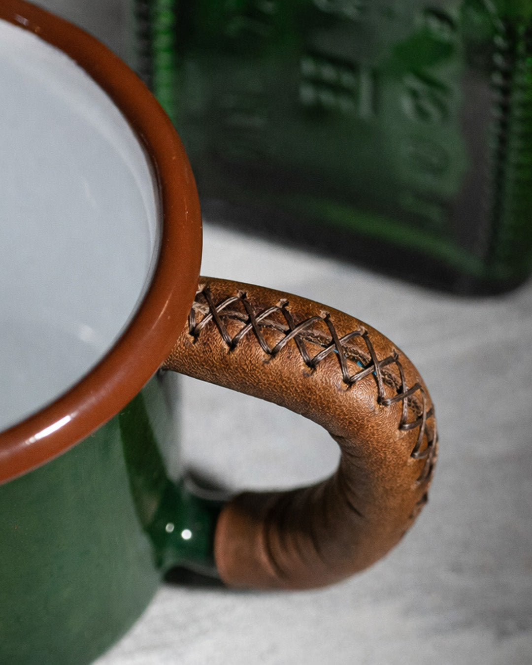 Detailed close-up of handcrafted leather handle wrapping showcasing quality stitching on green enamel outdoor mug
