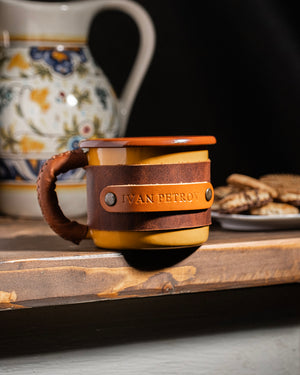 Dogaart yellow leather-wrapped enamel mug positioned on wooden table surface showing elegant front profile