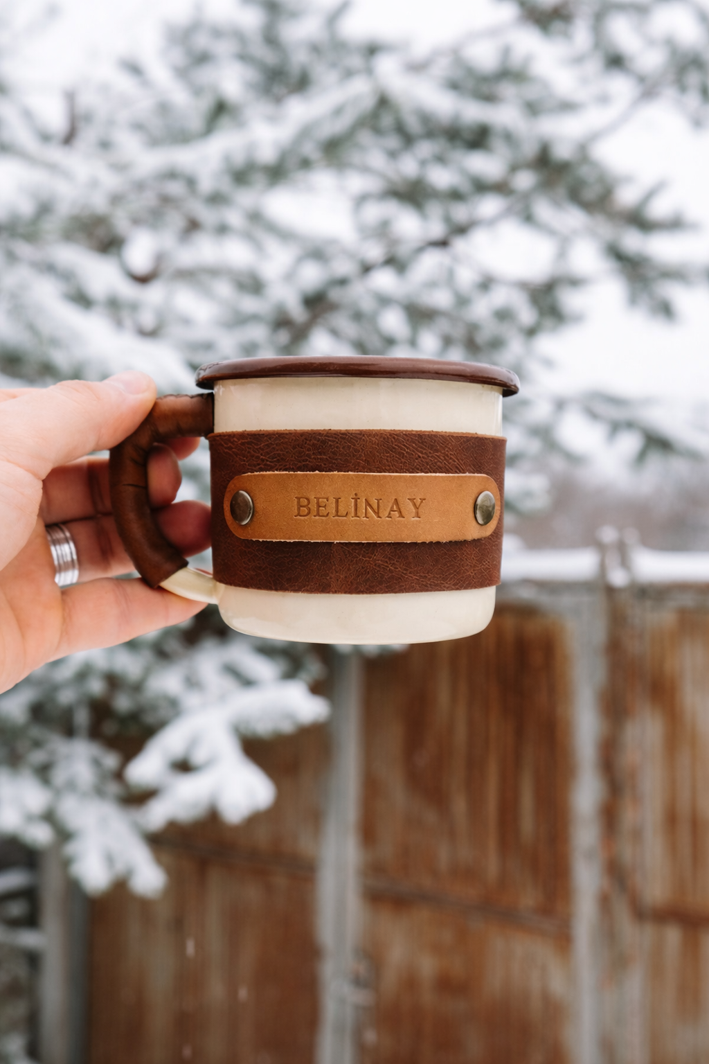 Travel mug with leather sleeve designed for outdoor adventures and comfortable grip, hand-held demonstration