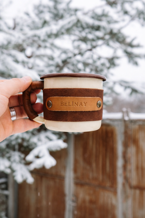 Travel mug with leather sleeve designed for outdoor adventures and comfortable grip, hand-held demonstration