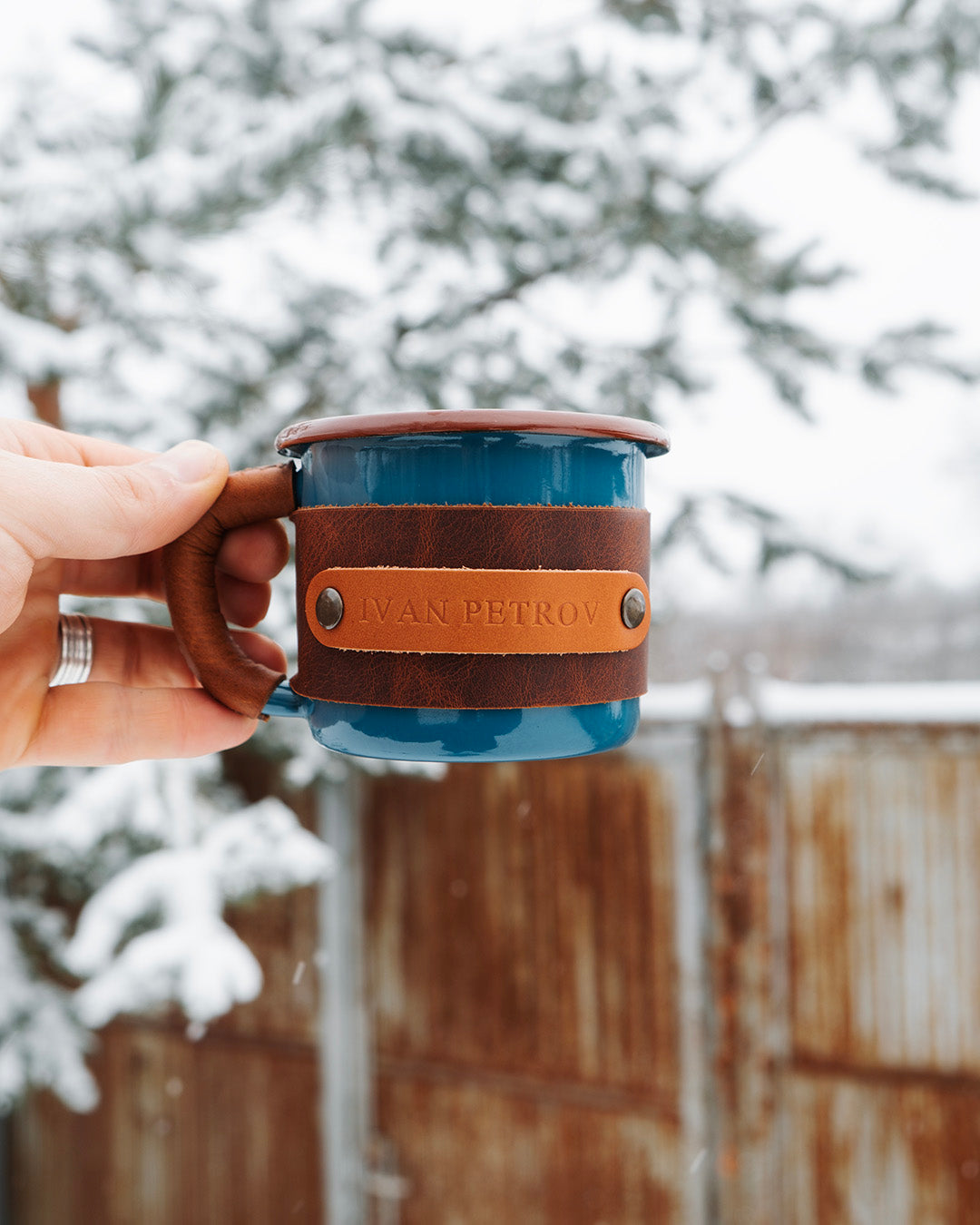Travel mug with leather sleeve designed for hiking and outdoor use, comfortable grip demonstration in hand