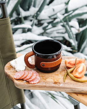 Rustic enamel mug with leather wrapping, ideal for camping and outdoor adventures, aerial view